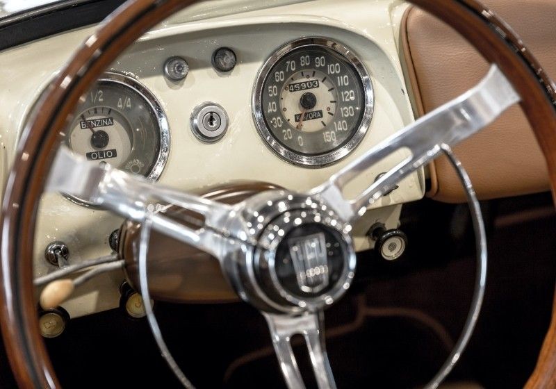 Vintage car dashboard seen from behind the wooden steering wheel, for the private driver service