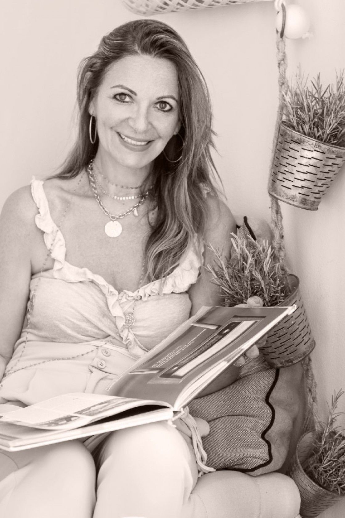 Black and white portrait of Anne Bernard, host of La Dolce Vita, seated with an open illustrated book