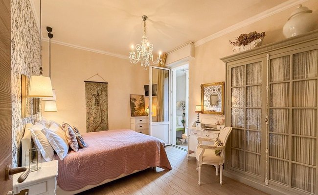 Madonna del Terraglio bedroom with a pink bedspread, a crystal chandelier and a glass-fronted wardrobe