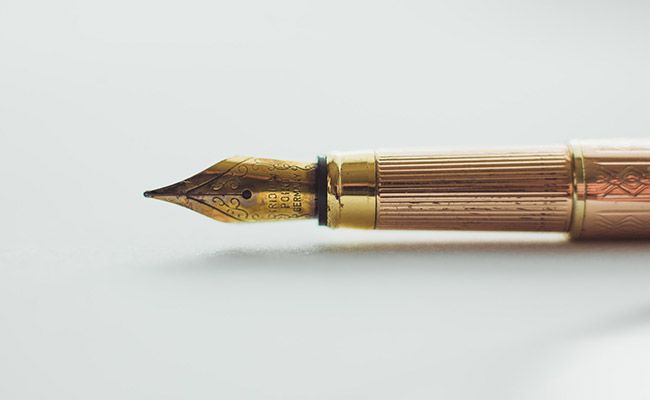 Gold fountain pen resting on a white surface