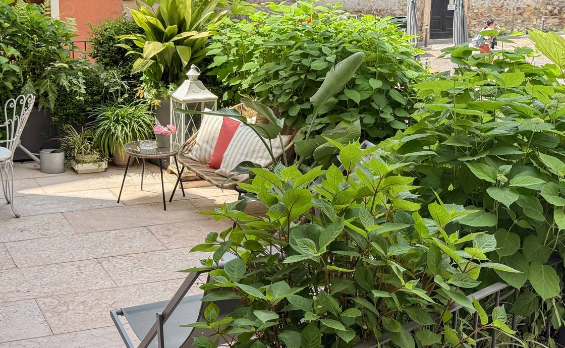 Paved private terrace at Santo Stefano with a white wrought-iron table and chairs among potted greenery
