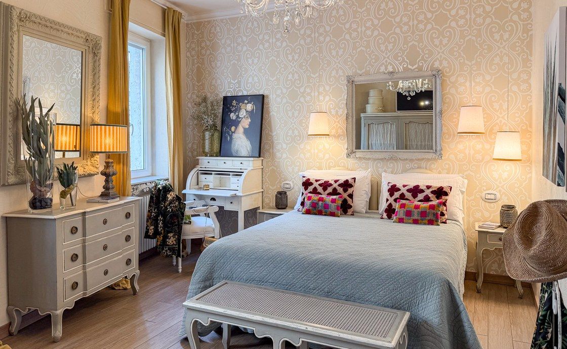 Bedroom at Madonna del Terraglio with a white writing desk, chandelier and yellow curtains