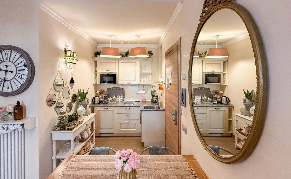 Cream kitchen at Madonna del Terraglio with a large gilt oval mirror and a table set with roses