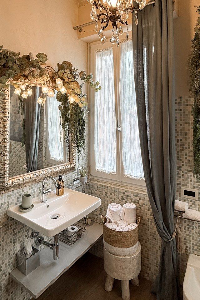 Mosaic-tiled bathroom at Madonna del Terraglio with a wall-hung basin and a mirror framed in foliage