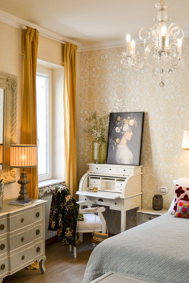 Writing corner in a Madonna del Terraglio bedroom, with a white secretaire and a floral portrait