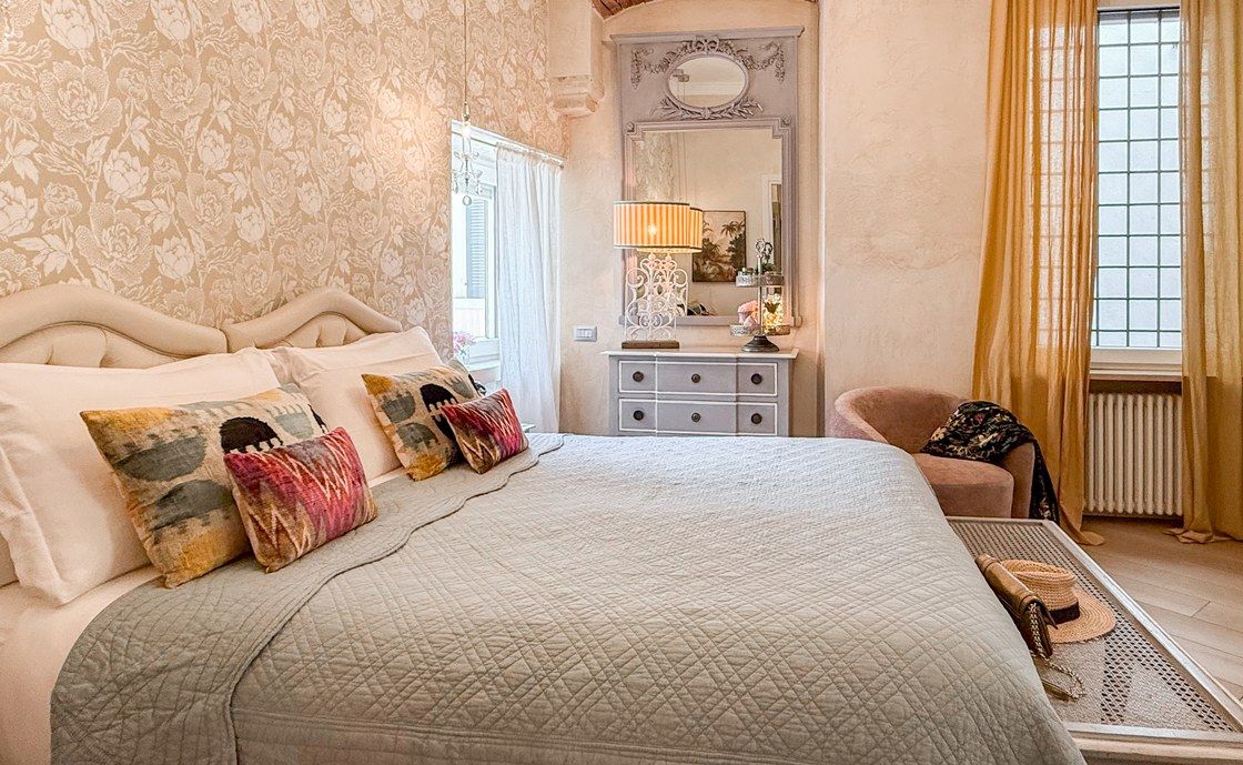 Double bed at Santo Stefano with a padded headboard, patterned cushions and a white chest of drawers