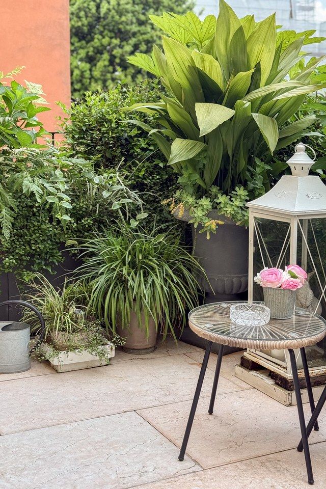 Corner of the Santo Stefano terrace with a white lantern and a round table holding pink roses